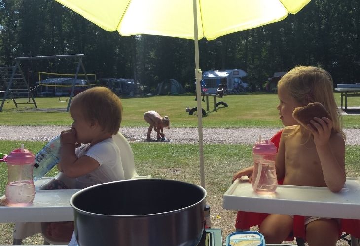 Kinderen in kinderstoel op camping parasol kamperen met baby tips