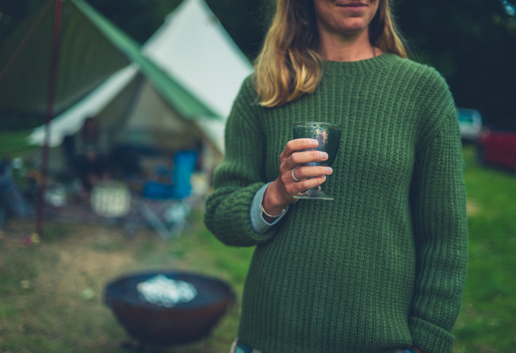Mevrouw in groene trui met wijn op de camping